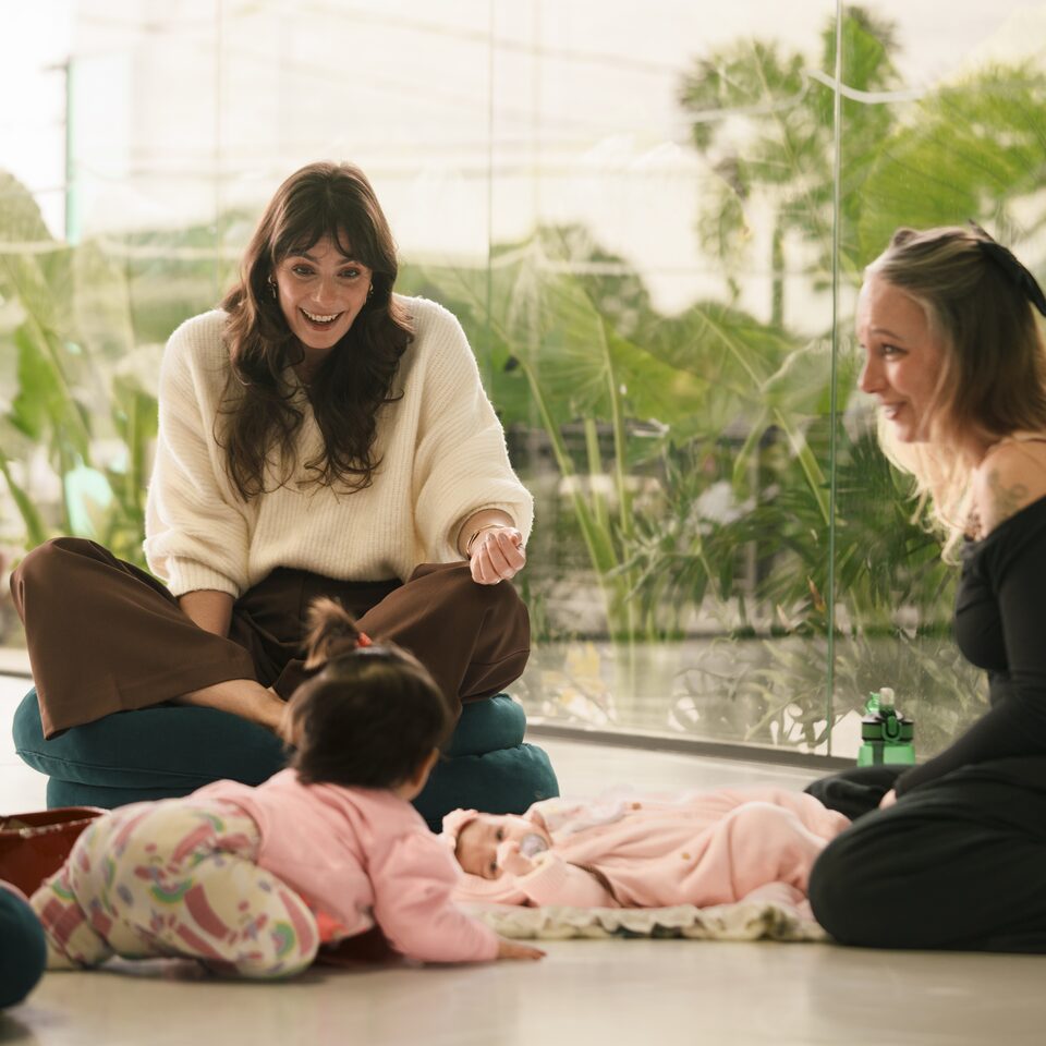Luciana Lima conversando com uma mãe durante um encontro, com o bebê no chão ao lado